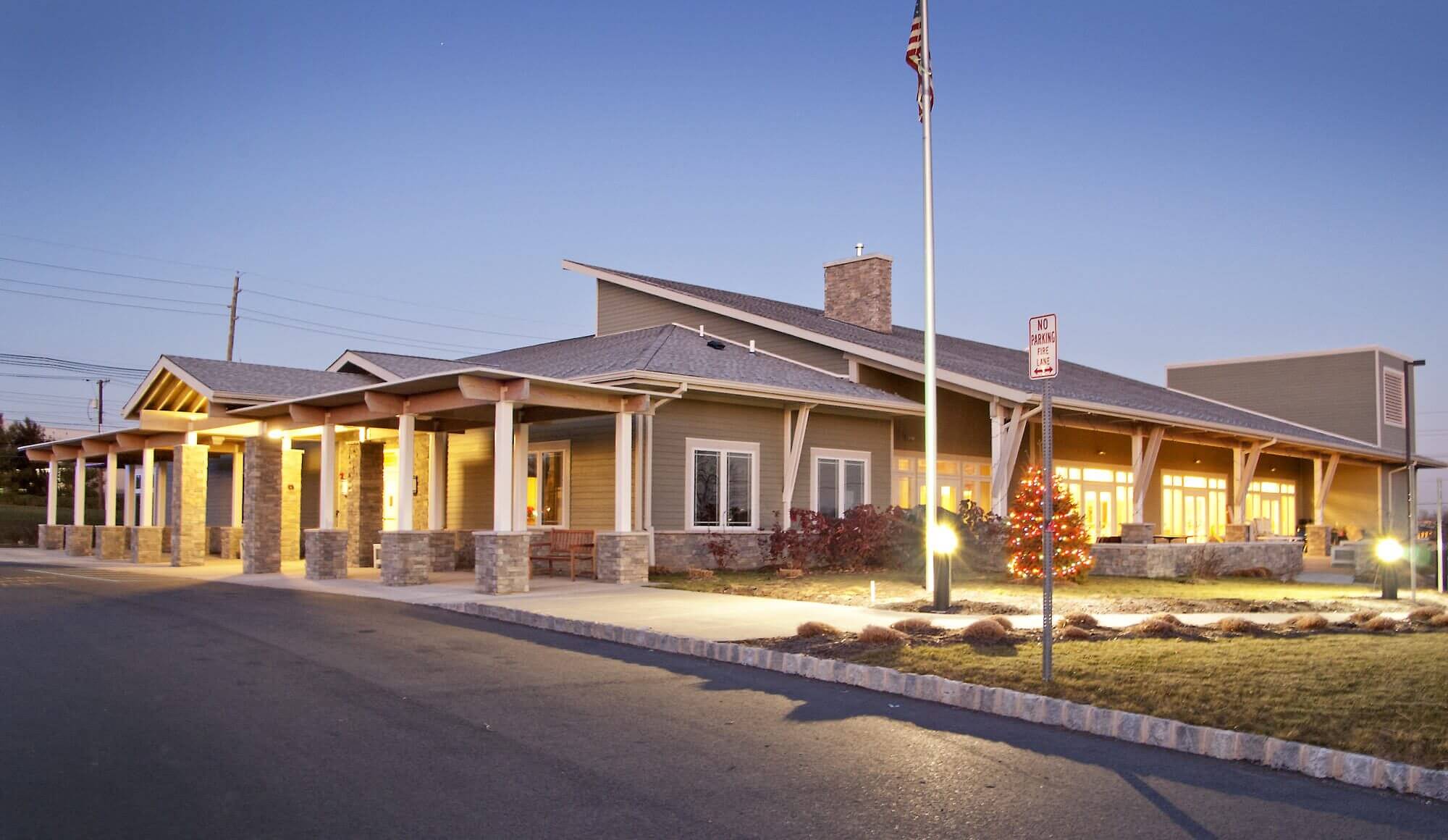 An assisted living building with an American flag on a flagpole outside of it.