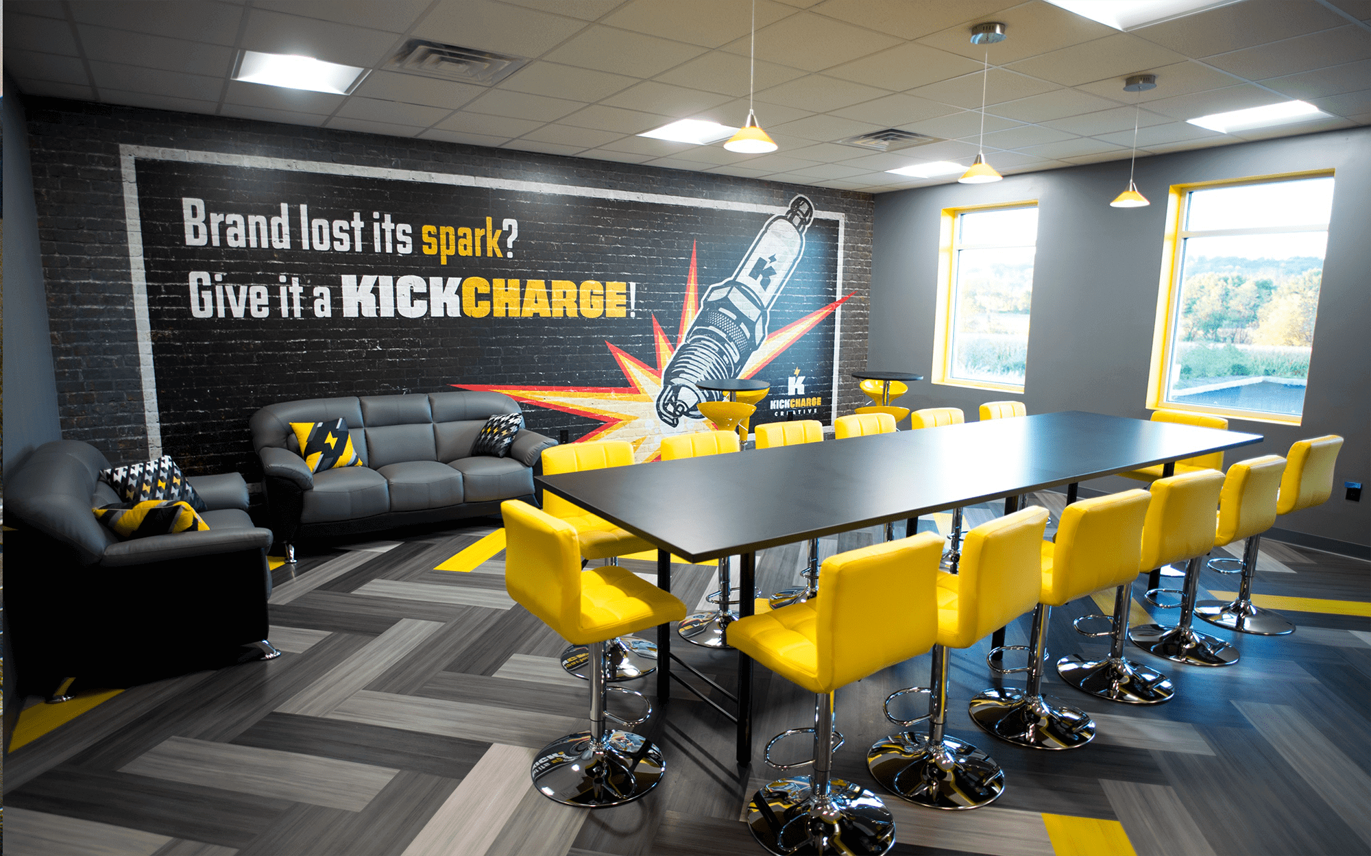 A conference room with black couches, and yellow stools around a conference table.