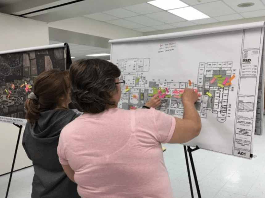 Two women working on a new building layout that is on an easel.