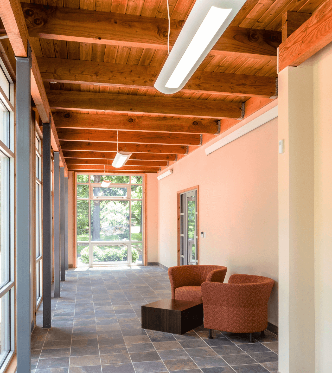 A front waiting room with a tiled floor, natural light coming through, and two red cushioned seats.