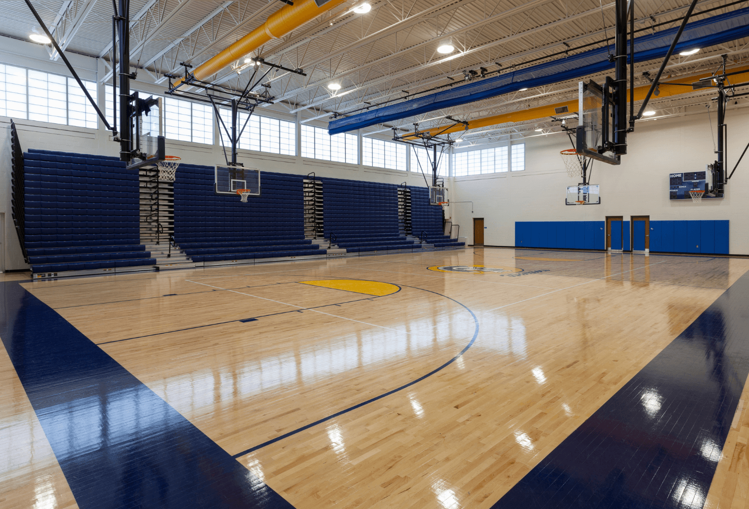 A school gym and basketball court with multiple hoops and seating.
