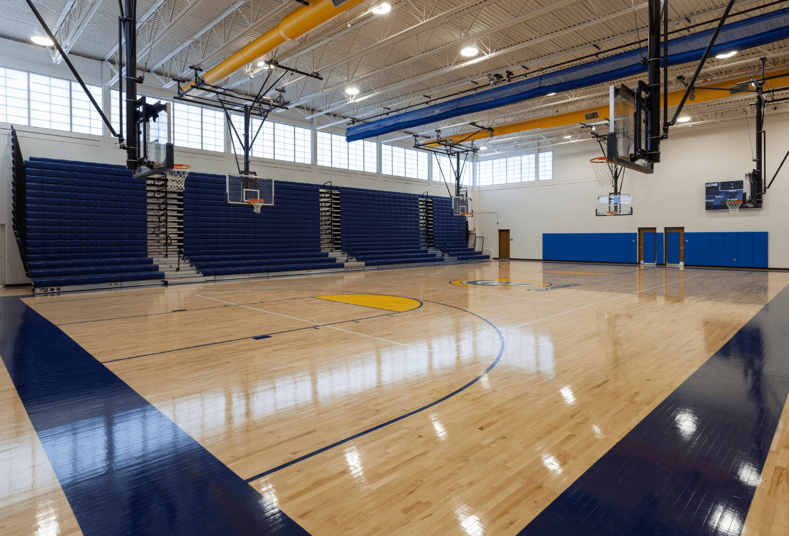 15 A school gym and basketball court with multiple hoops and seating.