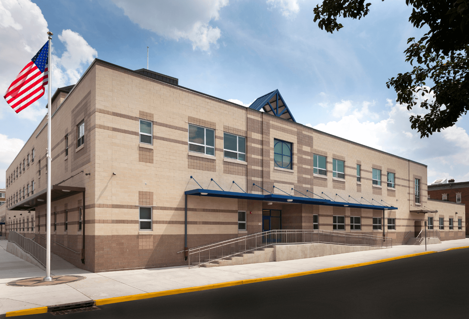 A design of a public school building with an American Flag on a flagpole outside of it.